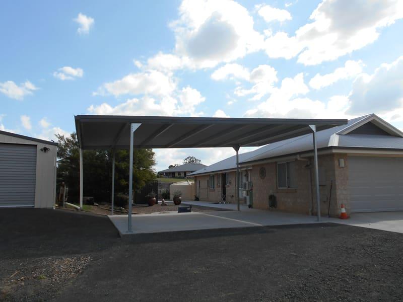 Flat-roof double carport beside a brick home