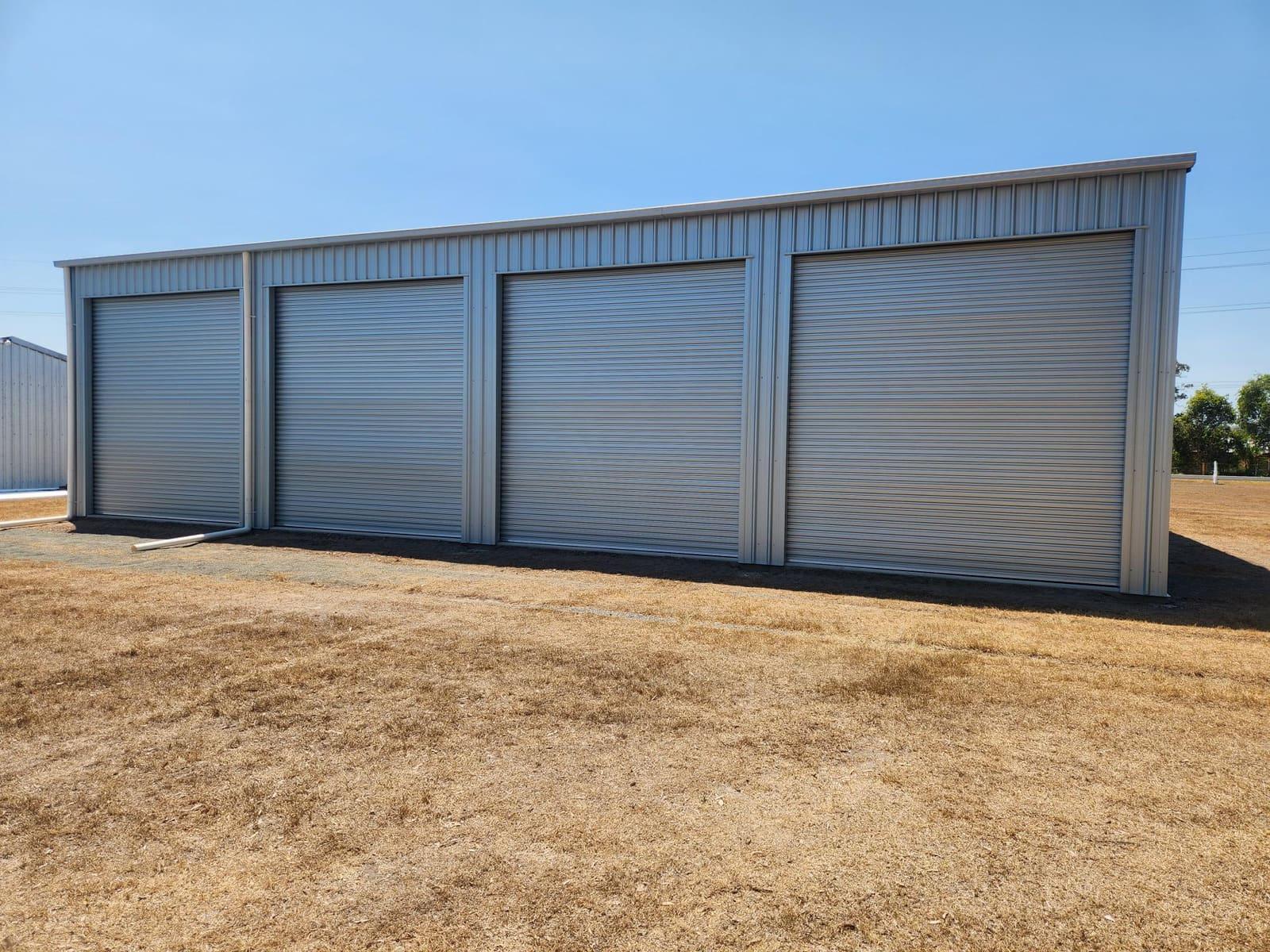Completed zincalume shed with four roller doors on a dry site